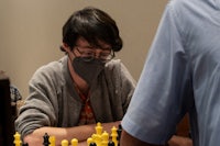 a young man wearing a face mask is playing chess